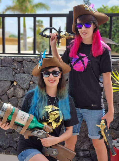 Two people with colorful hairstyles and hats holding toy guns outdoors.